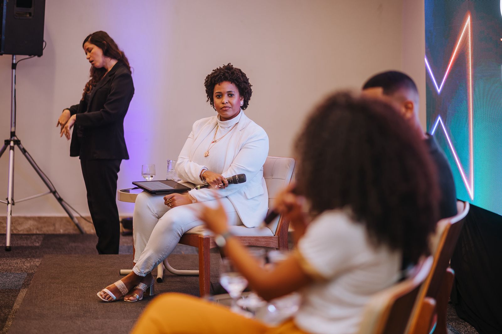 Fernanda Silva em painel de evento conduzindo com microfone